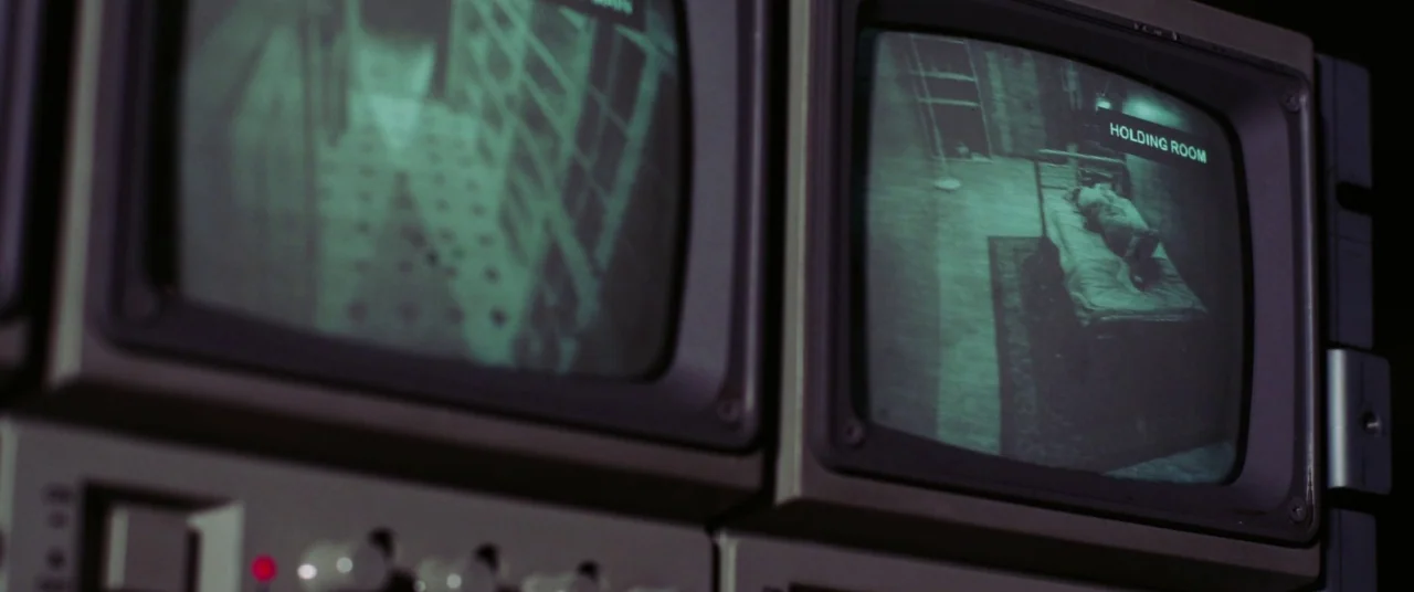 The Mind’s Eye (2015) movie still: medium — Two CRT security monitors display grainy green night-vision feeds of an interior space. One screen shows…