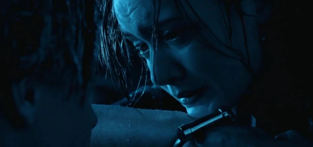 Titanic (1997) movie still: closeup — A dark, wet, nighttime setting on open water. A woman leans over to look at a man, holding his wet hand.