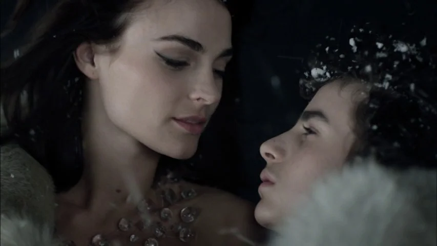 The Sleeping Beauty (2010) movie still: closeup — Two individuals face each other amidst falling snow in a dark, outdoor space. A woman in a…