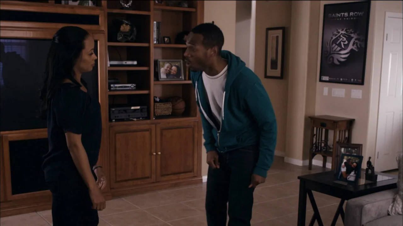 A Haunted House (2013) movie still: medium — A residential living room features light-colored floor tiles and wooden built-in shelving units. A man…