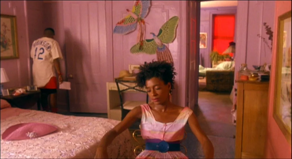 Do The Right Thing (1989) movie still: medium — A vibrant bedroom with lavender walls decorated with large ornamental butterfly cutouts. A woman…