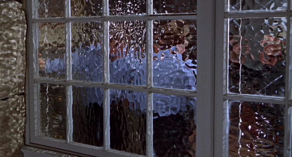 Fahrenheit 451 (1966) movie still: medium — A multi-pane window with textured glass reveals distorted shapes from an external dark area. The wooden…