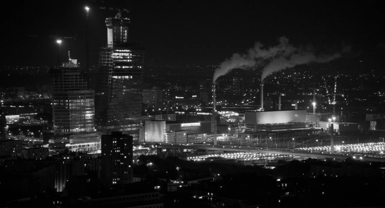 Paris, 13th District (2021) movie still: establishing — A panoramic nighttime city skyline view features unfinished high-rise buildings and…