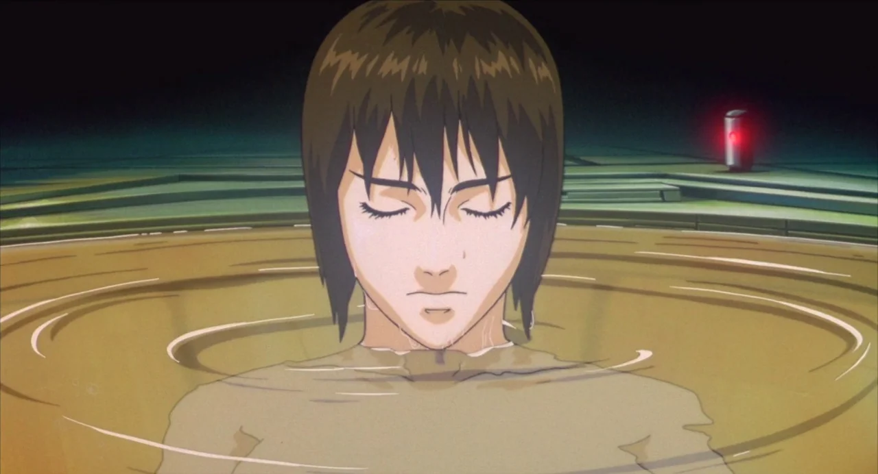 Ghost in the Shell (1995) movie still: medium — A woman is submerged to the shoulders in a translucent brownish liquid tank. A singular small red…