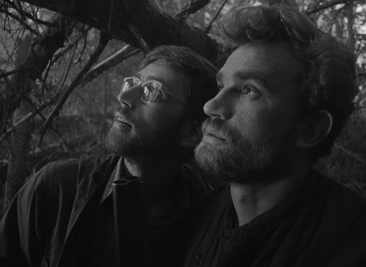 Letter Never Sent (1960) movie still: medium — A dense wooded area featuring overgrown branches and dark foliage in the background. Two men with…