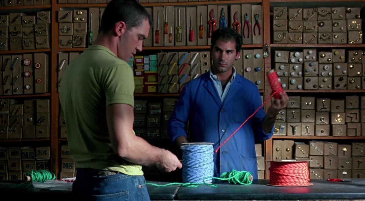 Tie Me Up! Tie Me Down! (1989) movie still: medium — A hardware store interior features floor-to-ceiling wooden shelving units filled with boxed…
