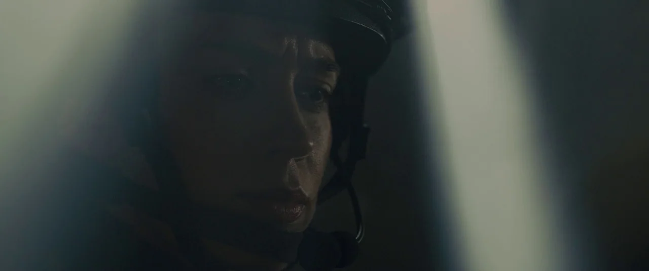 Sicario (2015) movie still: closeup — A dark environment provides the backdrop for a close-up on a woman's face. She wears a tactical headset and…