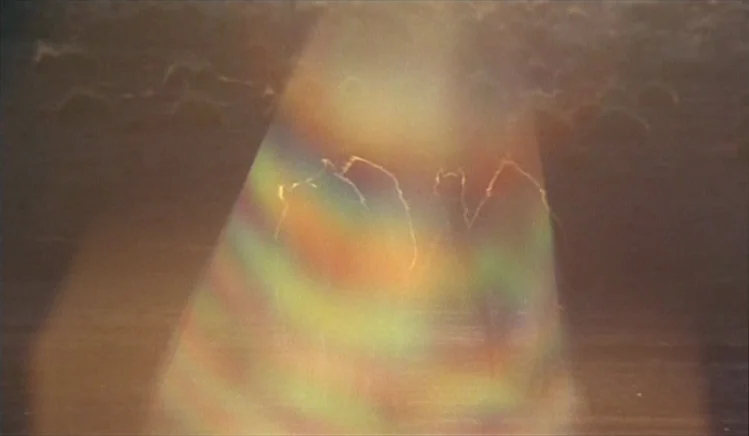 Walkabout (1971) movie still: wide — An expanse of water is shown under bright, hazy natural light conditions. A strong rainbow lens flare obscures…