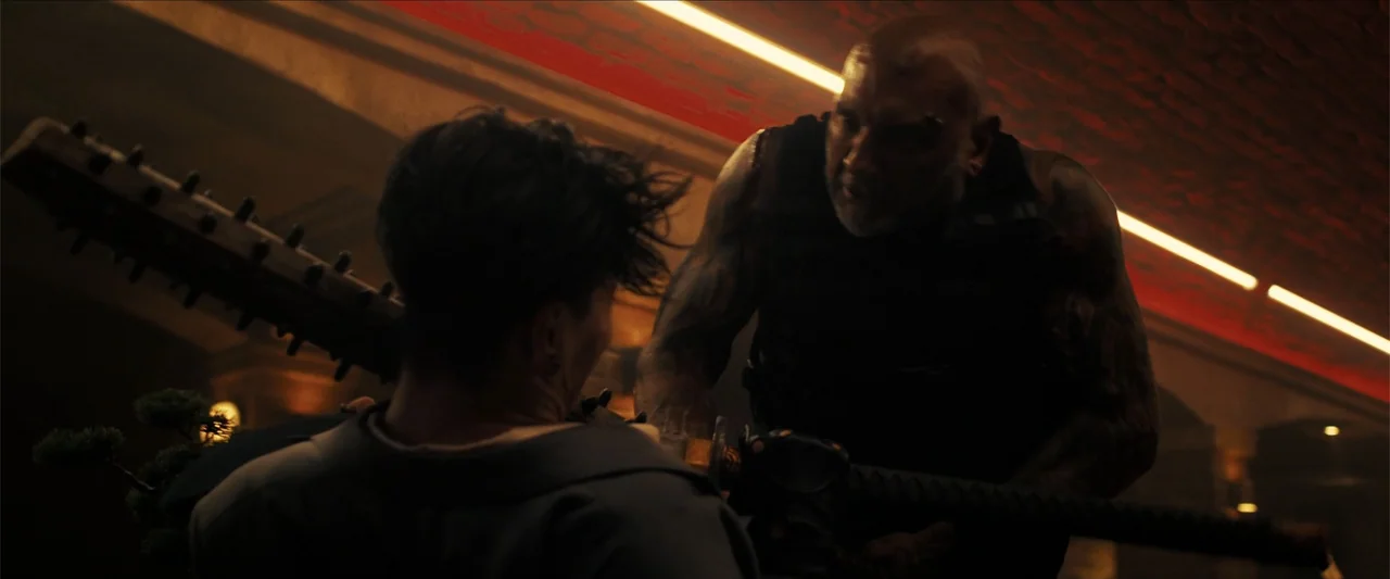 The Wrecking Crew (2026) movie still: medium — A dimly lit room with overhead red neon tubing and textured brick surfaces. A heavily tattooed man…