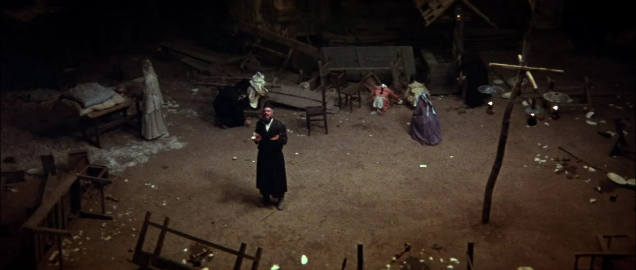 Fiddler On The Roof (1971) movie still: wide — A dark, dilapidated interior space is cluttered with scattered wooden debris and overturned…