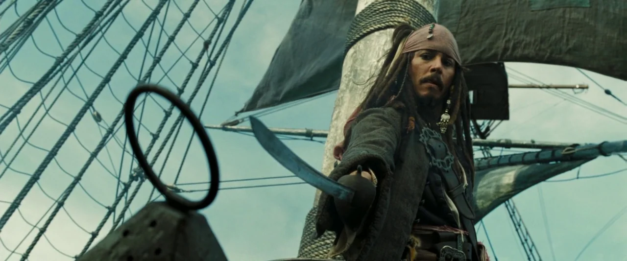 Pirates of the Caribbean: Dead Man’s Chest movie still: medium — A wooden ship deck is visible with thick rope rigging and a black sail. A man in…