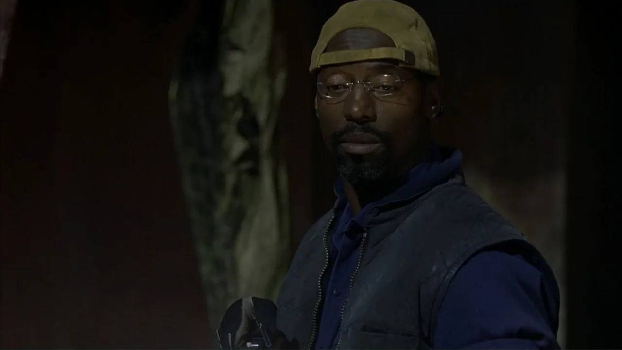 Ghost Ship (2002) movie still: medium — An interior space with dark walls and indistinct equipment in the background. A man stands in the foreground…