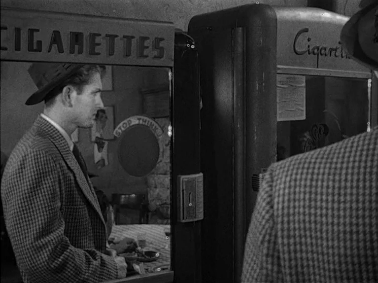 The Big Night (1951) movie still: medium — A dimly lit interior space features two vintage cigarette vending machines placed side-by-side. A man…