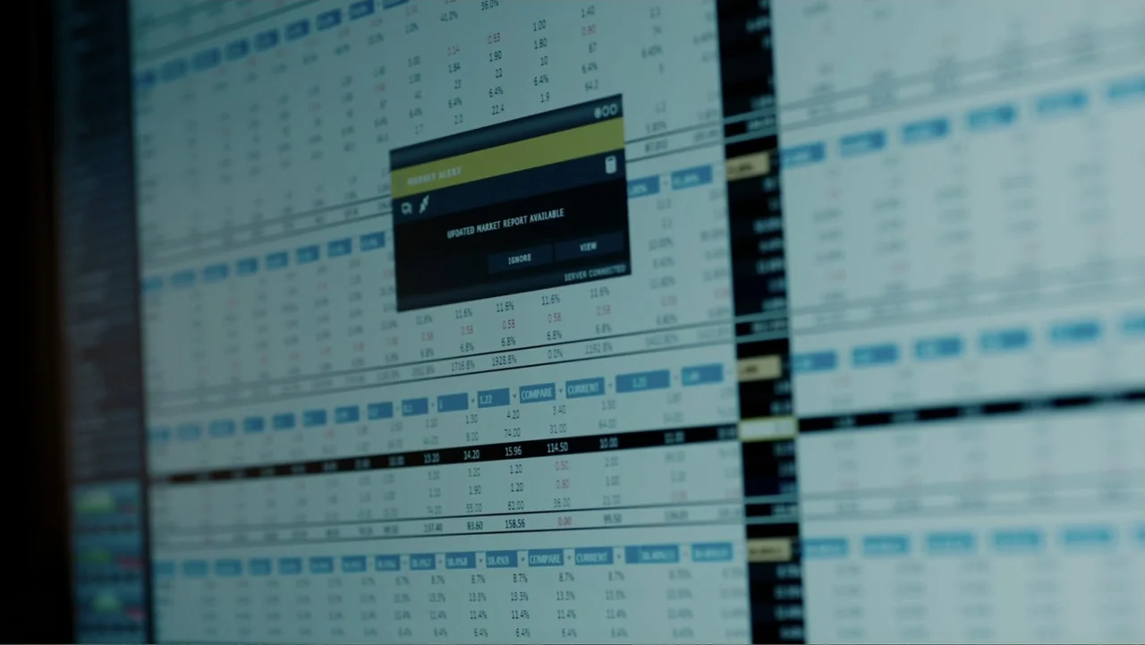 A Cure for Wellness (2017) movie still: closeup — A close-up view shows a computer monitor displaying a financial data spreadsheet interface. A dark…