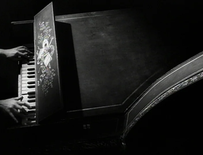 The Devil’s Eye (1960) movie still: closeup — A dark, high-contrast environment centers on the keyboard of an antique harpsichord. Hands are visible…