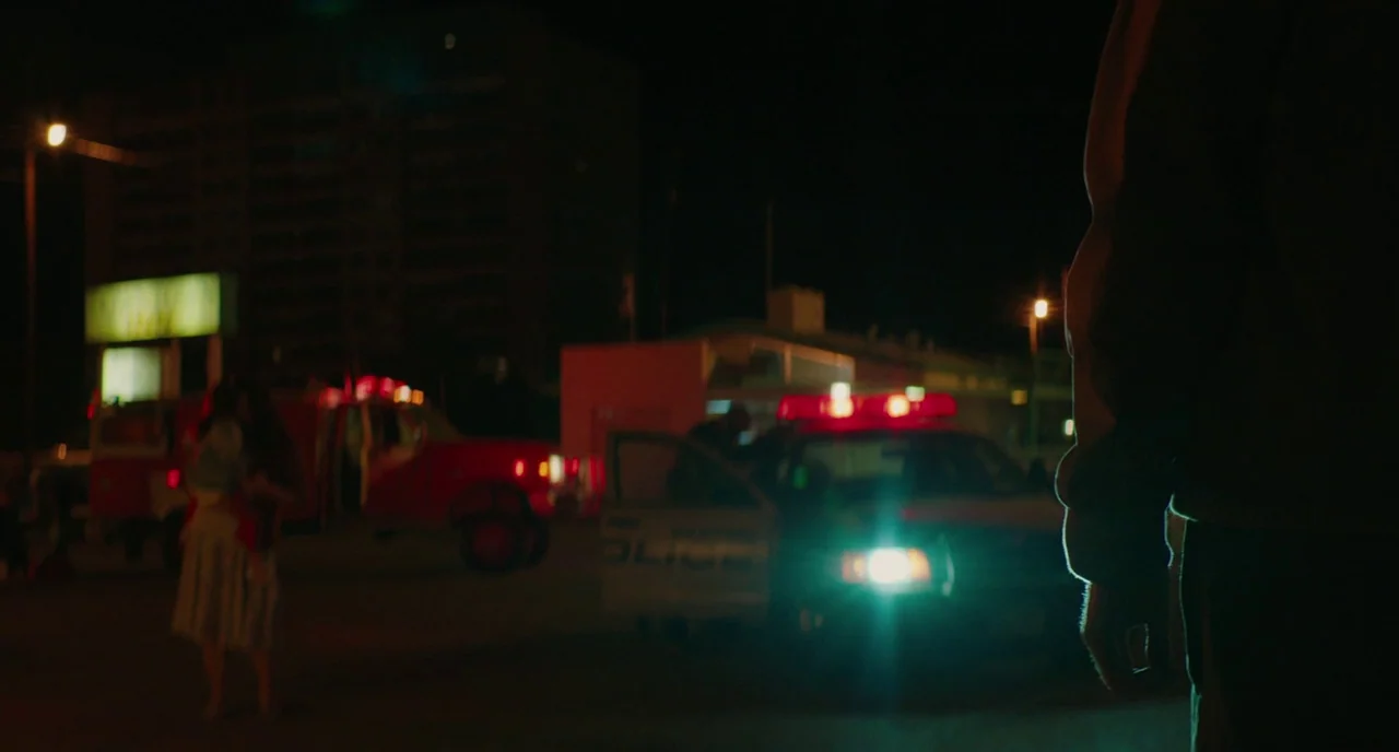 Fast Color (2018) movie still: medium — A nighttime scene in a paved lot featuring a police cruiser and fire truck. A shadowed figure stands in the…