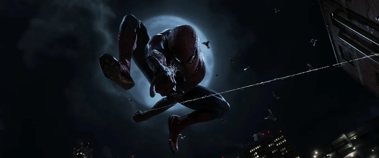The Amazing Spider-Man (2012) movie still: fullbody — A figure in a textured red and blue suit leaps through the night sky. A bright full moon…