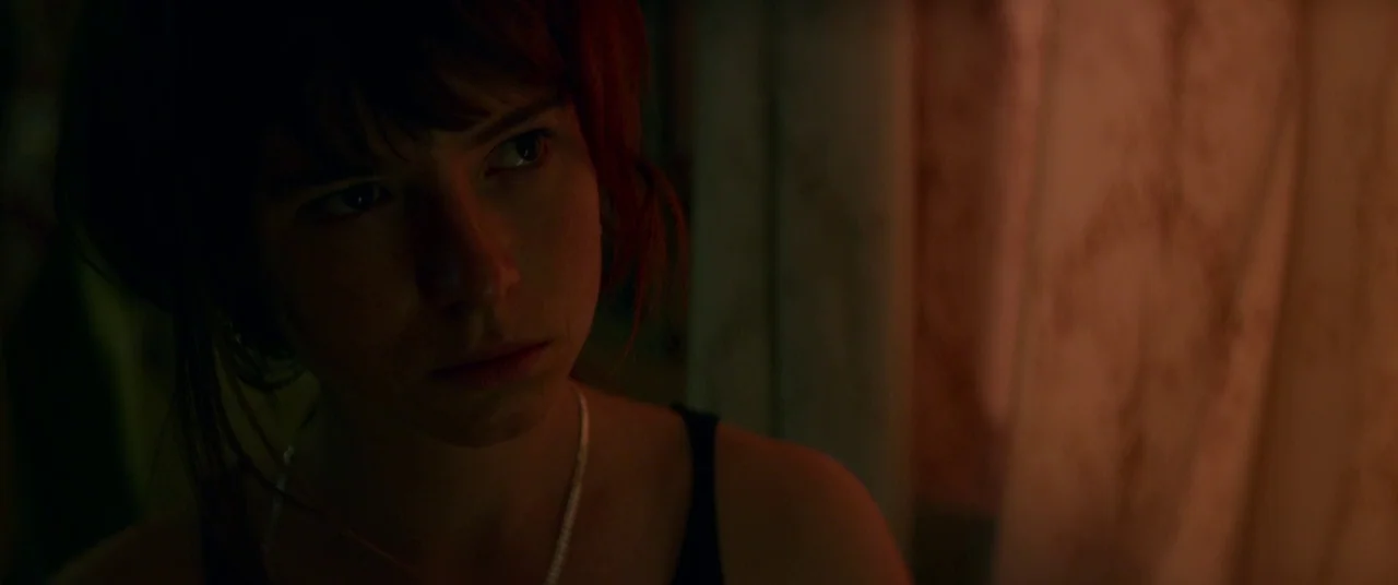 Wild Rose (2018) movie still: closeup — A dimly lit indoor space features textured wall coverings illuminated by warm light. A woman with dark hair…