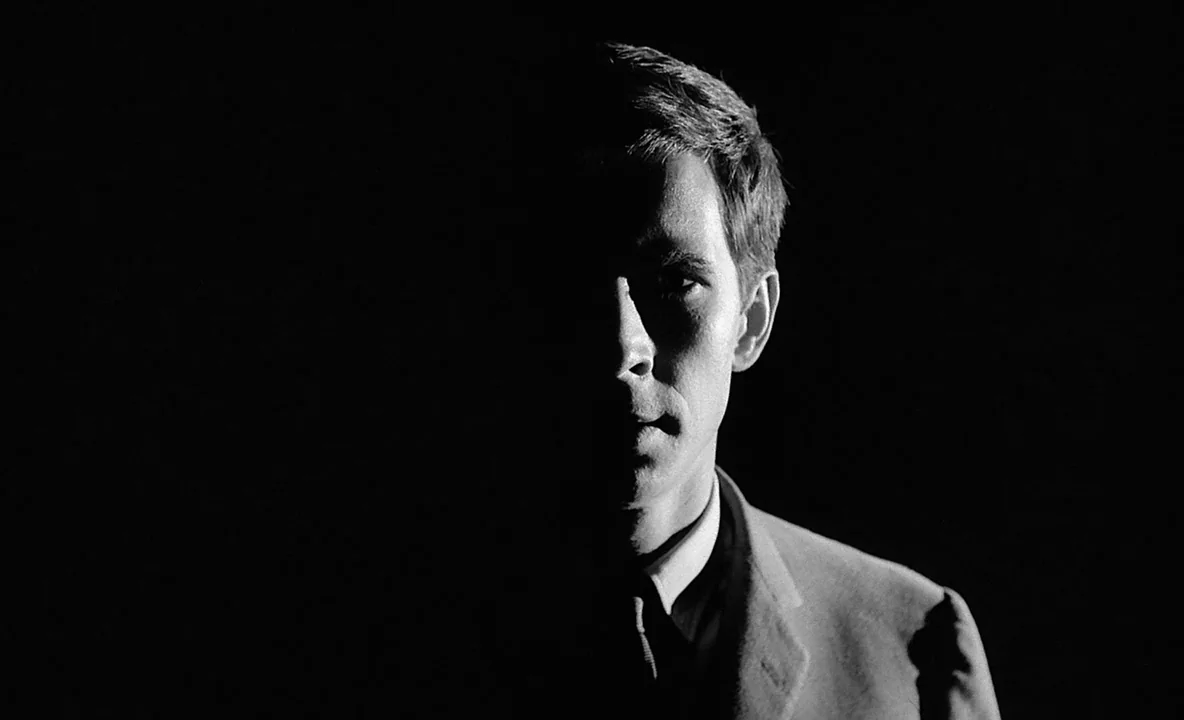 The Trial (1962) movie still: closeup — A man stands in a completely dark space with no visible background elements. He is lit from the side…
