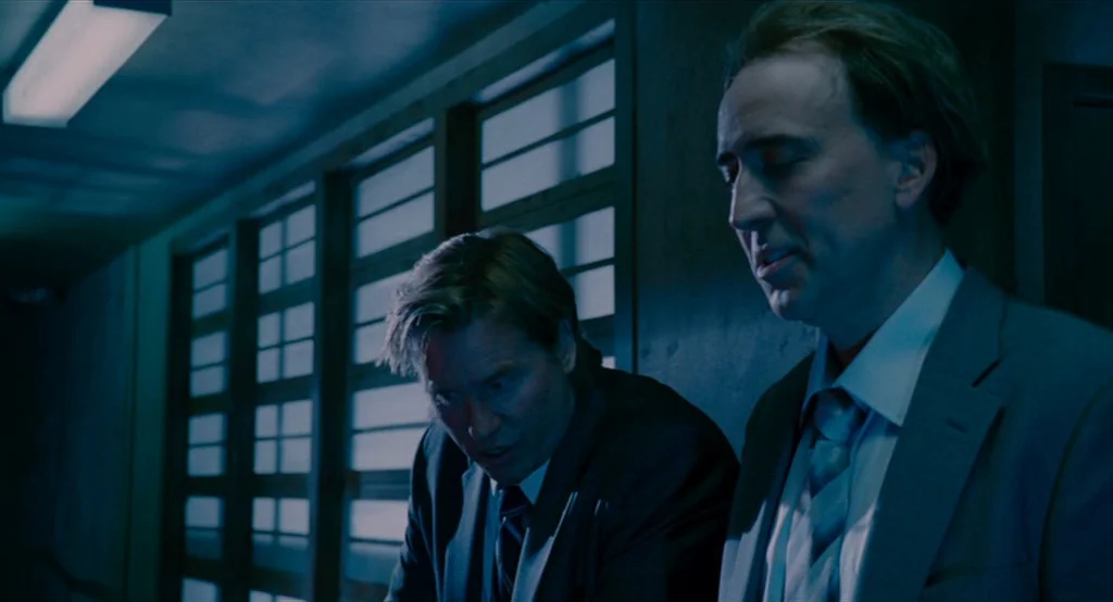 Bad Lieutenant: Port Of Call New Orleans (2009) movie still: medium — Two men stand in a dim workspace with horizontal light filtering through…