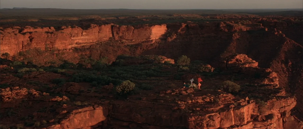 The Adventures of Priscilla, Queen of the Desert (1994) movie still: wide — A vast, arid desert canyon with layered red sandstone cliffs under clear…