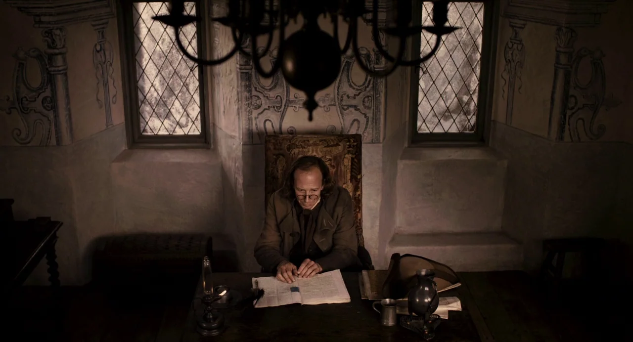 Mirror Mirror (2012) movie still: medium — A dimly lit historical workspace features stone walls with hand-painted murals and two tall windows. A…