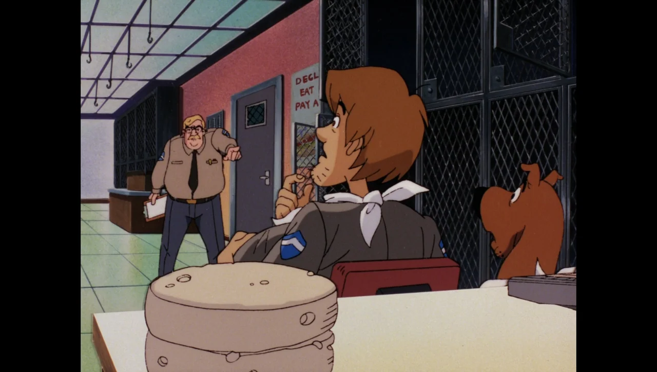Scooby-Doo on Zombie Island (1998) movie still: medium — An interior police station office with metal cages and a desk foreground. A stout officer…