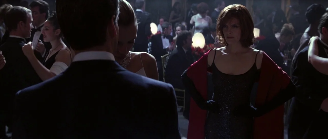 The Thomas Crown Affair (1999) movie still: medium — A dark ballroom filled with dancing couples and glowing table centerpieces. A woman in a black…