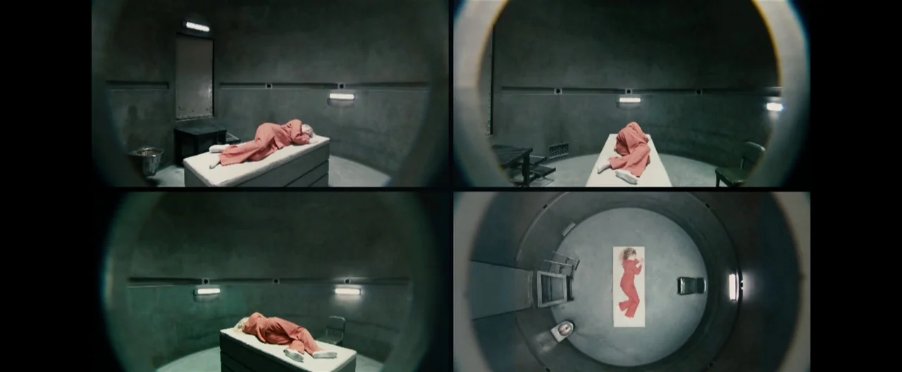 Hanna (2011) movie still: wide — A circular concrete room features a single cot and a small metallic corner unit. A woman rests on the cot while the…