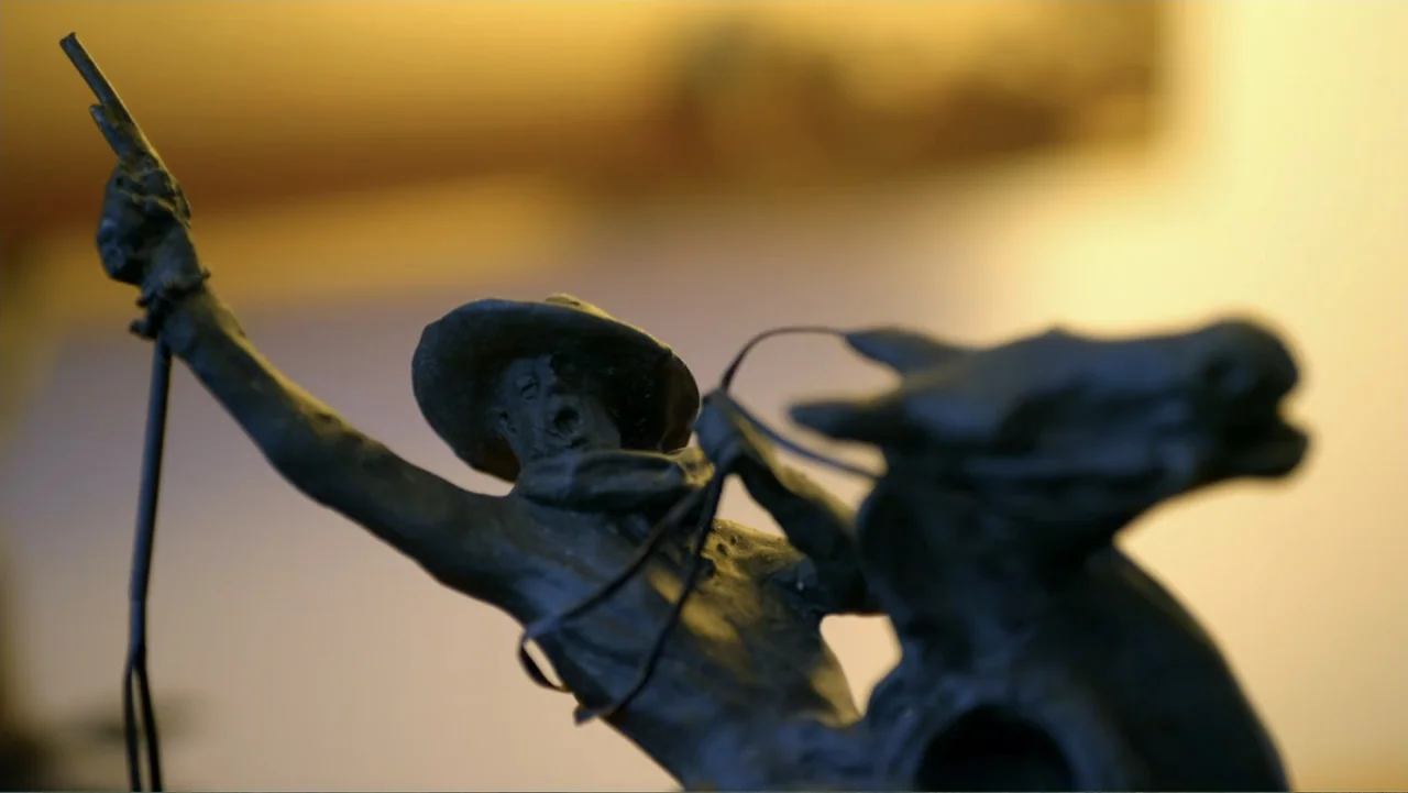 The Day the Music Died: The Story of Don McLean's "American Pie" (2022) movie still: closeup — A close view shows a small bronze sculpture depicting…