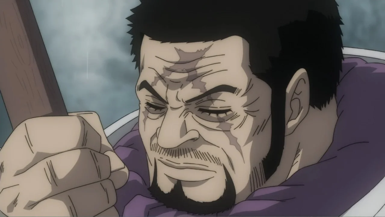 One Piece Film Red (2022) movie still: closeup — A man with a distinct scar over his eyes stands in an outdoor location. He grips a wooden staff in…