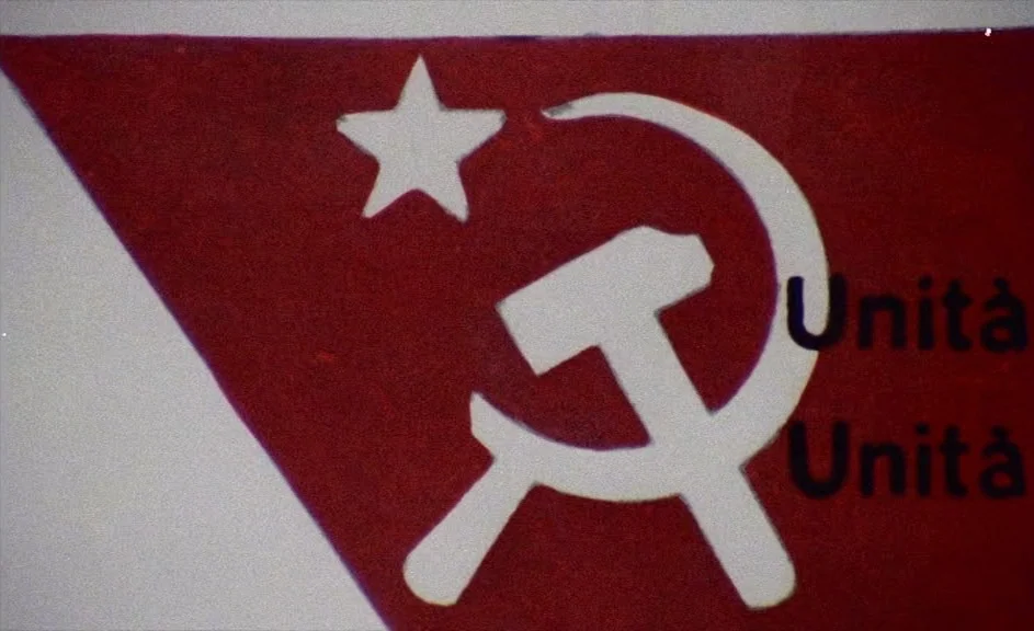 The Kingdom of Naples (1978) movie still: closeup — A red painted surface displays the white hammer and sickle symbol and a white star. To the right…