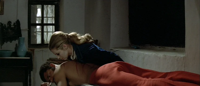 Whity (1971) movie still: medium — A spartan room features rough white walls, a single paneled window, and a small table. A woman leans over a…