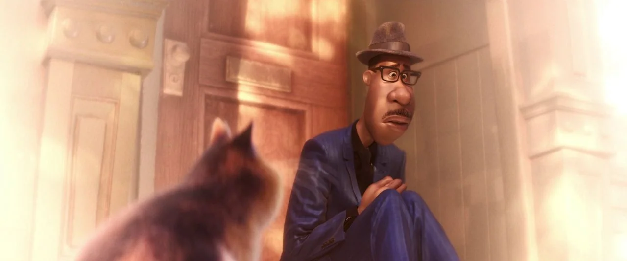 Soul (2020) movie still: medium — A man in a sharp blue suit kneels on a floor near a door. He gazes at a blurred cat in the foreground while bathed…