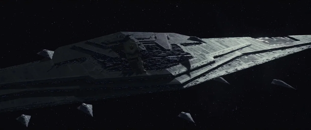 Star Wars: The Last Jedi (2017) movie still: wide — A massive, wedge-shaped capital starship dominates the frame in the vacuum of space. Several…