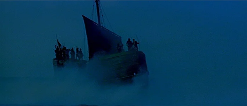 Erik The Conqueror (1961) movie still: wide — A wooden ship travels through dark water surrounded by dense, low-hanging blue fog. Several figures…