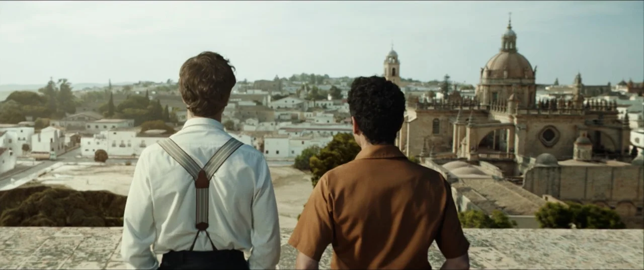 Hear Me: Our Summer (2024) movie still: medium — Two men overlook a sprawling Mediterranean-style town with a large domed cathedral. They stand on…