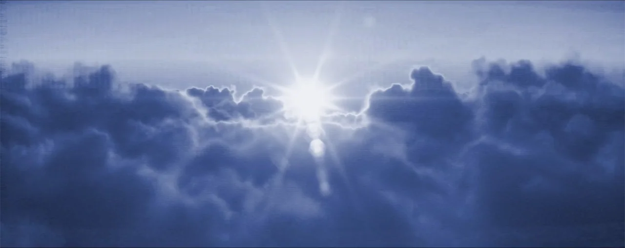 El Último Juego (2025) movie still: establishing — A dense layer of dark blue clouds fills the frame. The bright sun pierces through the center of…
