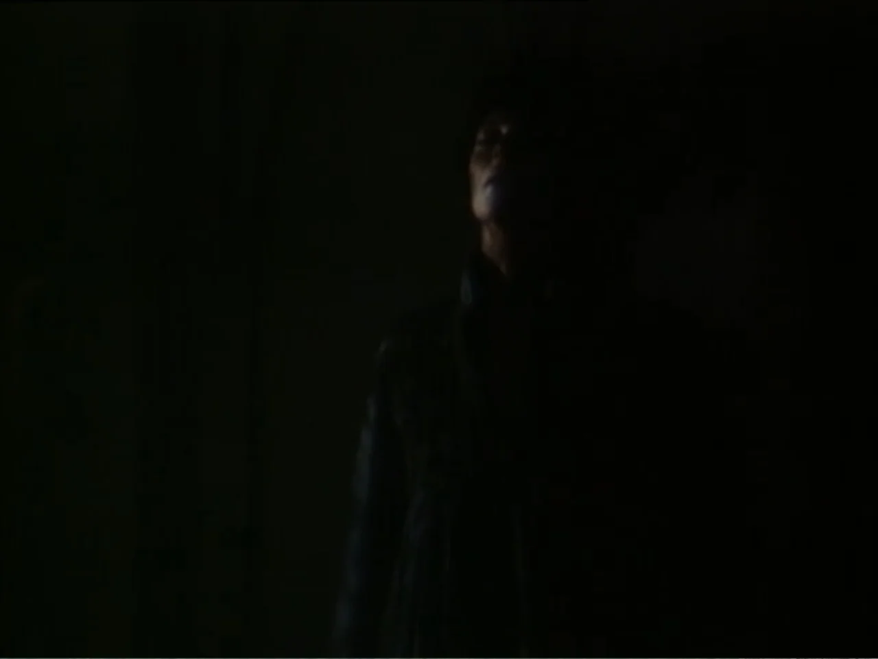 Curtains (1995) movie still: medium — A pitch black interior space obscures all architectural details behind the subject. A man in a dark coat…