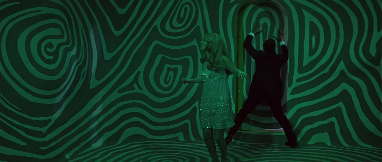 Casino Royale (1967) (1967) movie still: fullbody — An interior space features curved walls covered in a hypnotic, black and green pattern. A man…