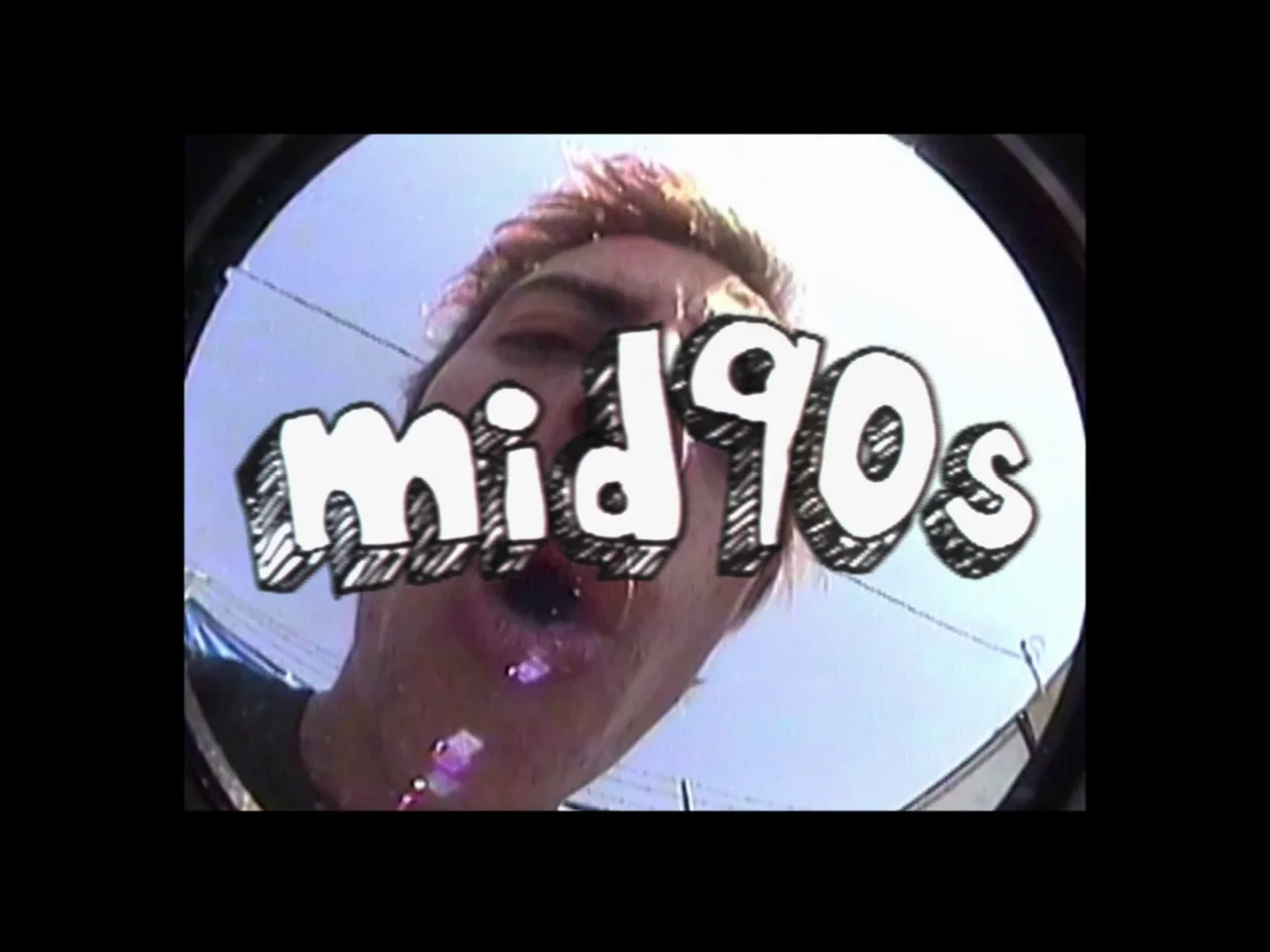 Mid90s (2018) movie still: closeup — An extreme close-up low-angle shot captures a person looking into a fisheye camera lens. The white graphic text…