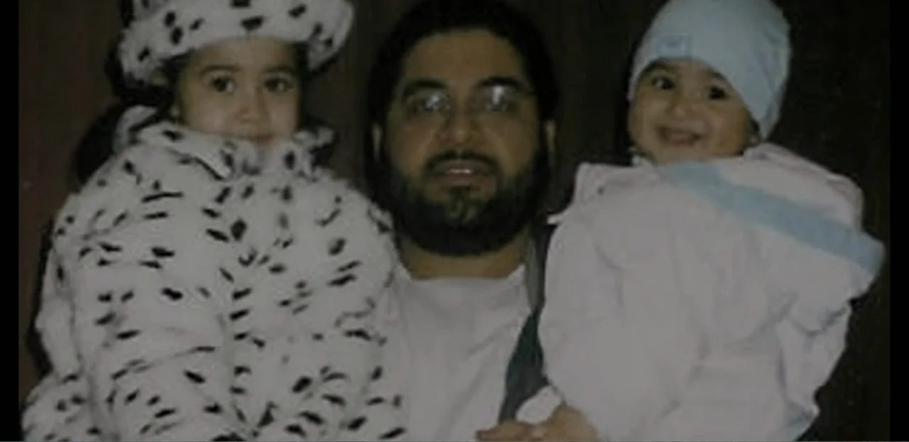 Doctors of the Dark Side (2011) movie still: medium — A man holds two young children close in an interior residential setting. The man stands…