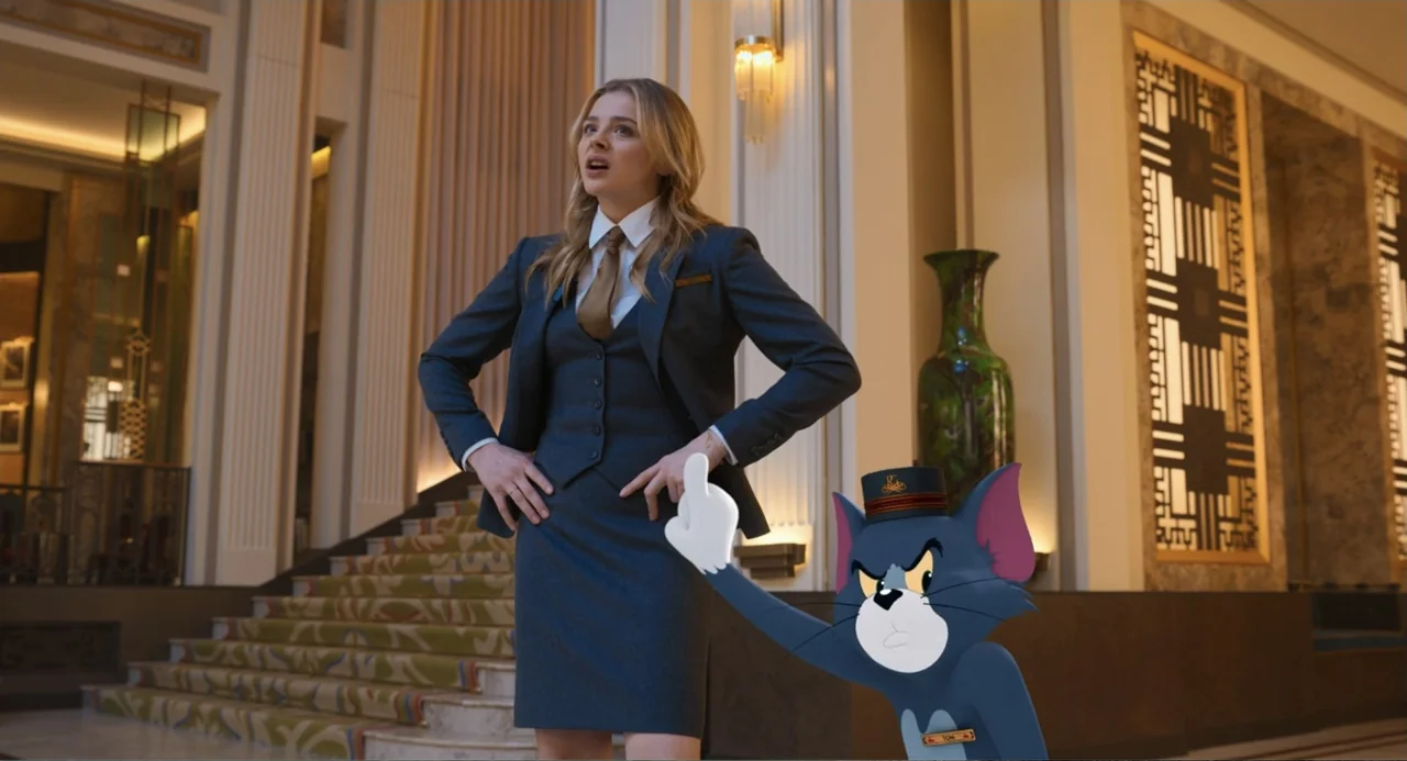 Tom & Jerry (2021) movie still: fullbody — A luxury hotel lobby features ornate columns and a staircase with patterned carpet. A young woman in a…
