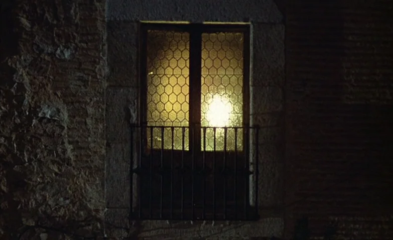 Spirit Of The Beehive (1973) movie still: medium — A stone building wall features a rectangular window with leaded geometric glass panes. A bright…