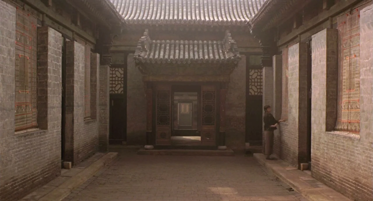 Raise The Red Lantern movie still: wide — A traditional Chinese courtyard features symmetrical brick buildings with tiled roofs and latticed wooden…