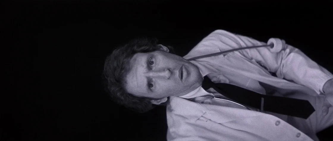 Carlito’s Way (1993) movie still: medium — A man in a white lab coat is positioned against a solid black background. He looks directly at the camera…