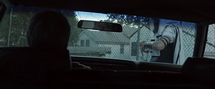To Dust - Nightmares (2018) movie still: medium — A view from the backseat of a car looking out at a residential building. A man in religious…