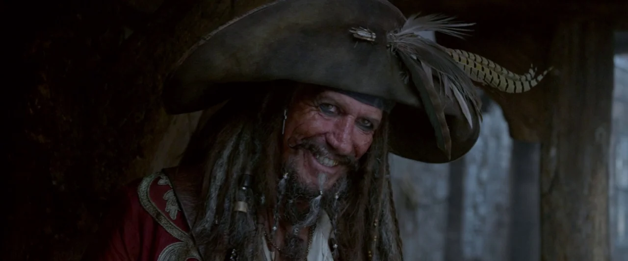 Pirates of the Caribbean: On Stranger Tides movie still: closeup — A dimly lit interior with wooden textures and shadow-filled corners surrounding…