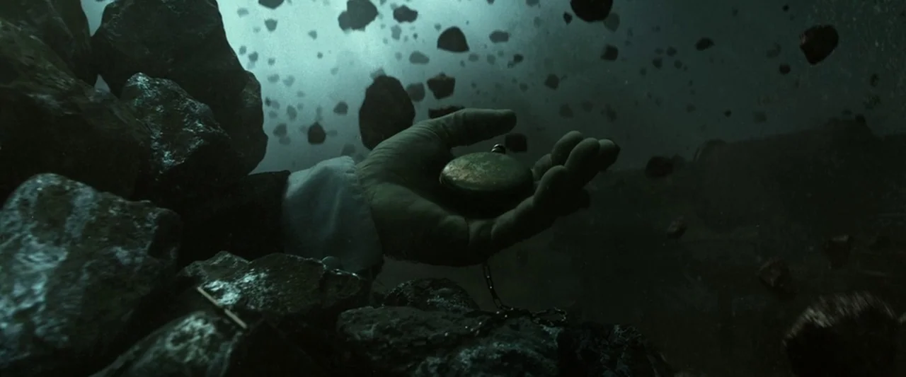 The Lone Ranger (2013) movie still: closeup — A dark, empty space is filled with floating rocks of varying sizes. A man's hand reaches into the…