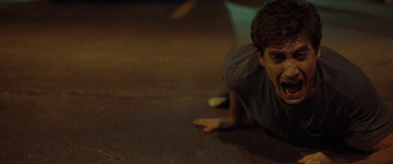 Stronger (2017) movie still: medium — A man crawls across a dark asphalt surface lit by artificial street lighting. He is face-down on the ground…